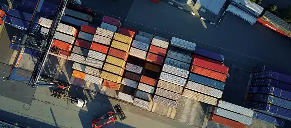 Yığılmış yük konteynerleriyle uluslararası konteyner nakliye terminalinin havadan görünümü.