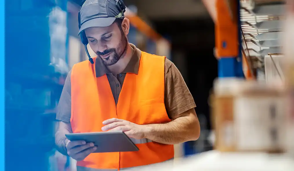 Depo çalışanı, bir depolama tesisinde envanter ve lojistik operasyonlarını yönetmek için tablet kullanıyor.